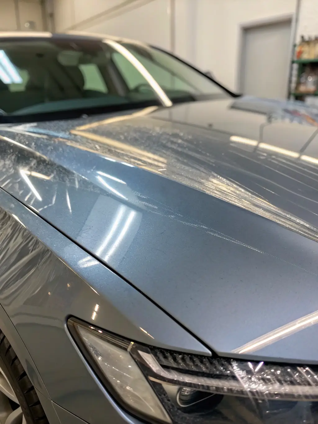 Close-up of a car hood with a clear protective film, highlighting the glossy finish and protective qualities of AutoSkinz's paint protection film.