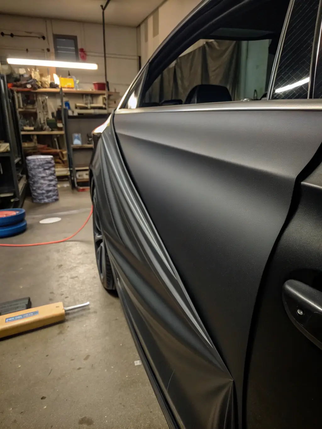 A close-up shot of a car door being expertly wrapped with a vibrant, glossy color change film, showcasing the precision and seamless finish achieved by AutoSkinz.